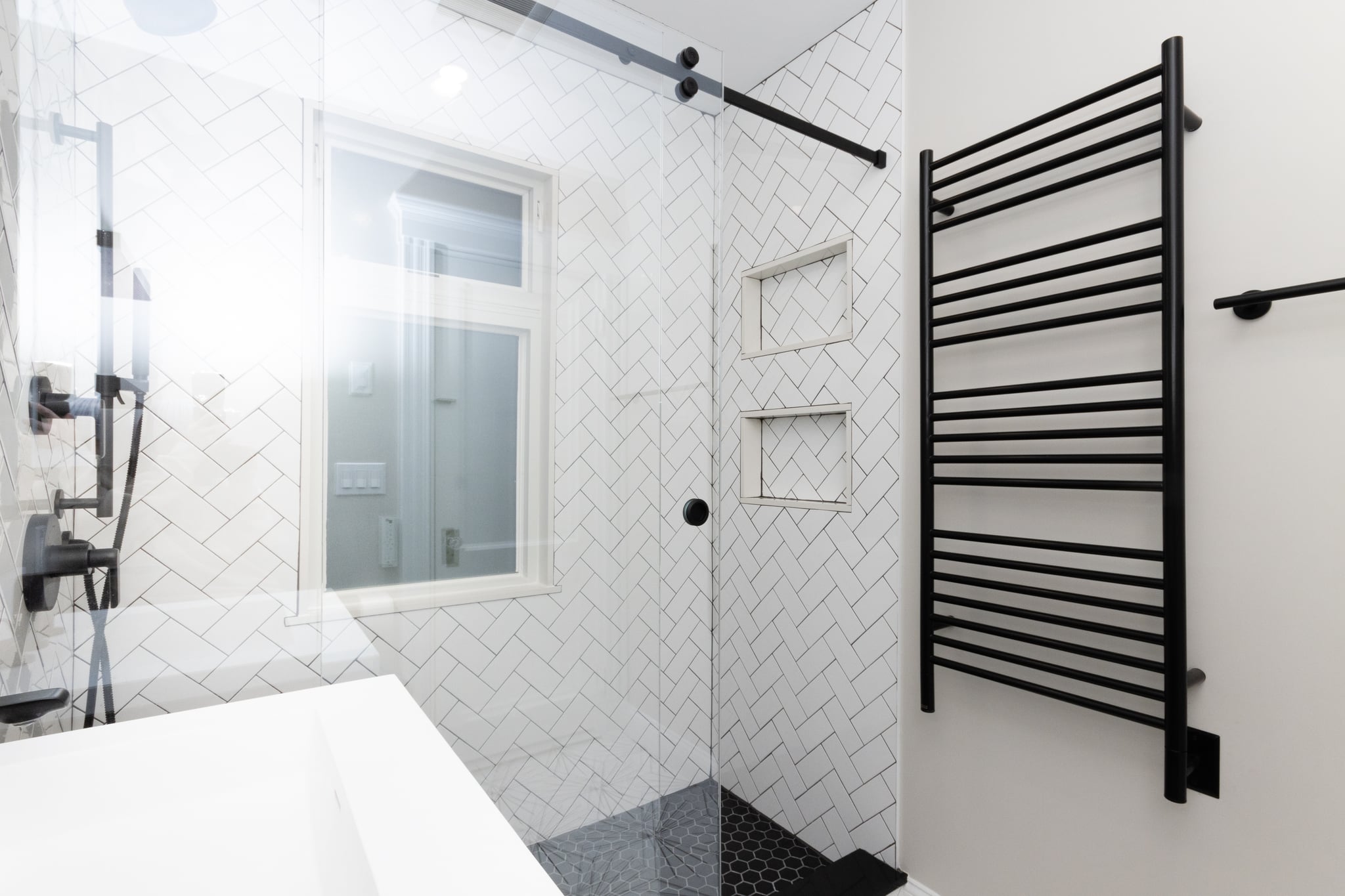 Modern bathroom remodel ideas with walk-in glass shower, white subway tile, black hex floor, and matte black fixtures