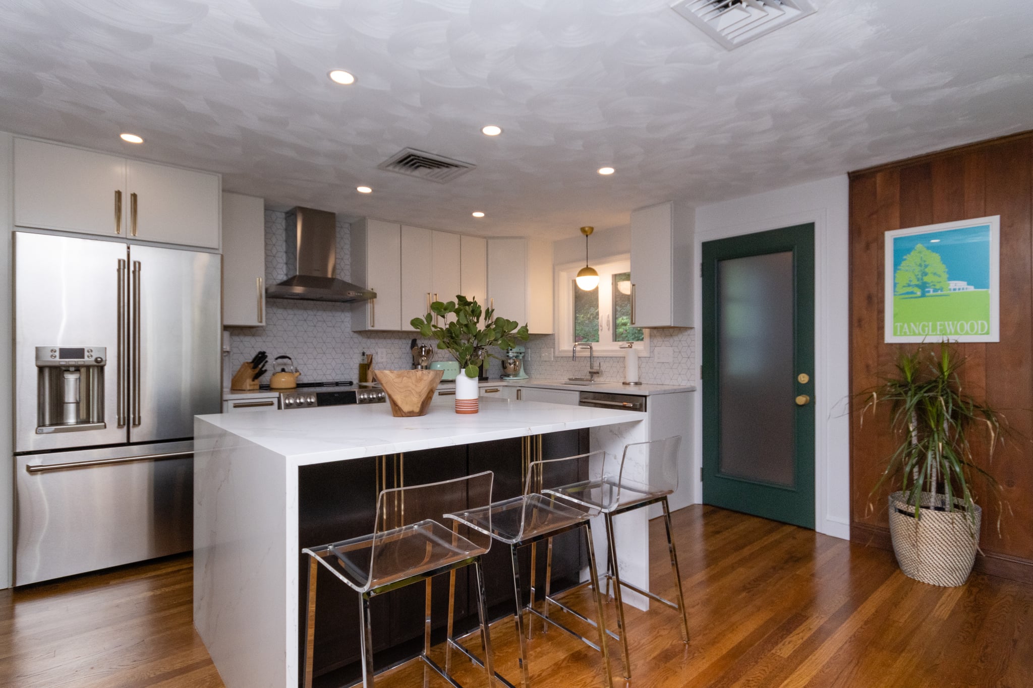 Open concept kitchen remodel with white cabinetry, hardwood floors, and ample natural light from large windows.