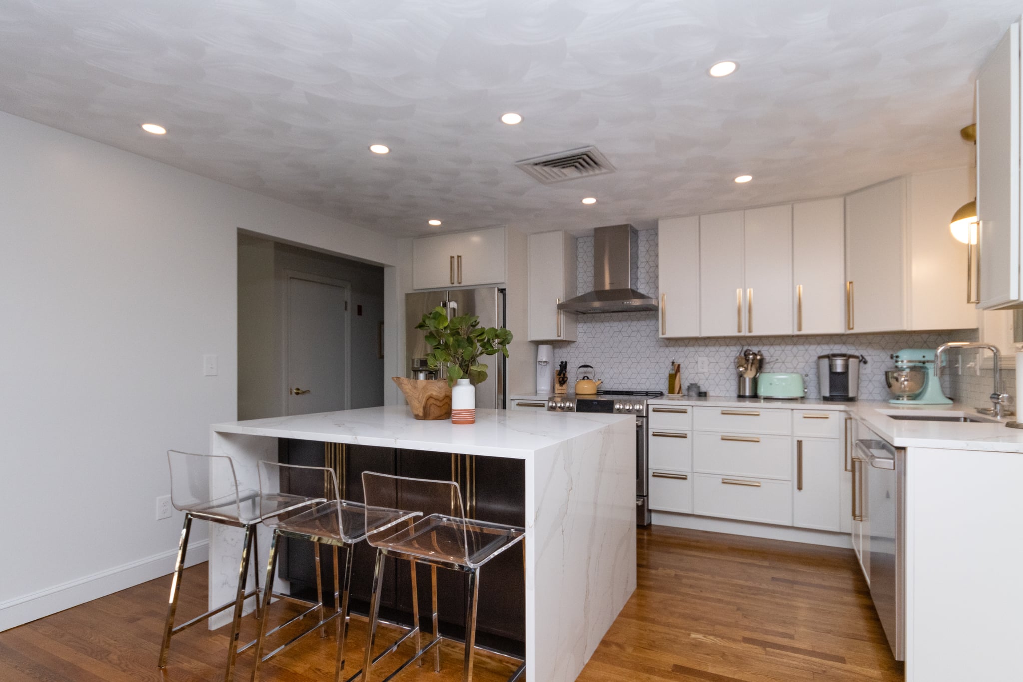 Bright and spacious newly remodeled kitchen with white cabinets, stainless steel appliances, and wooden floors.